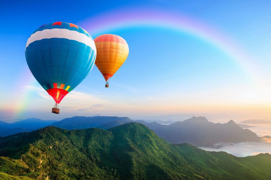 Two hot air balloons flying over a mountain range.