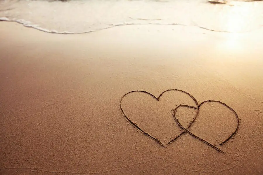 Two hearts drawn in the sand on a beach.