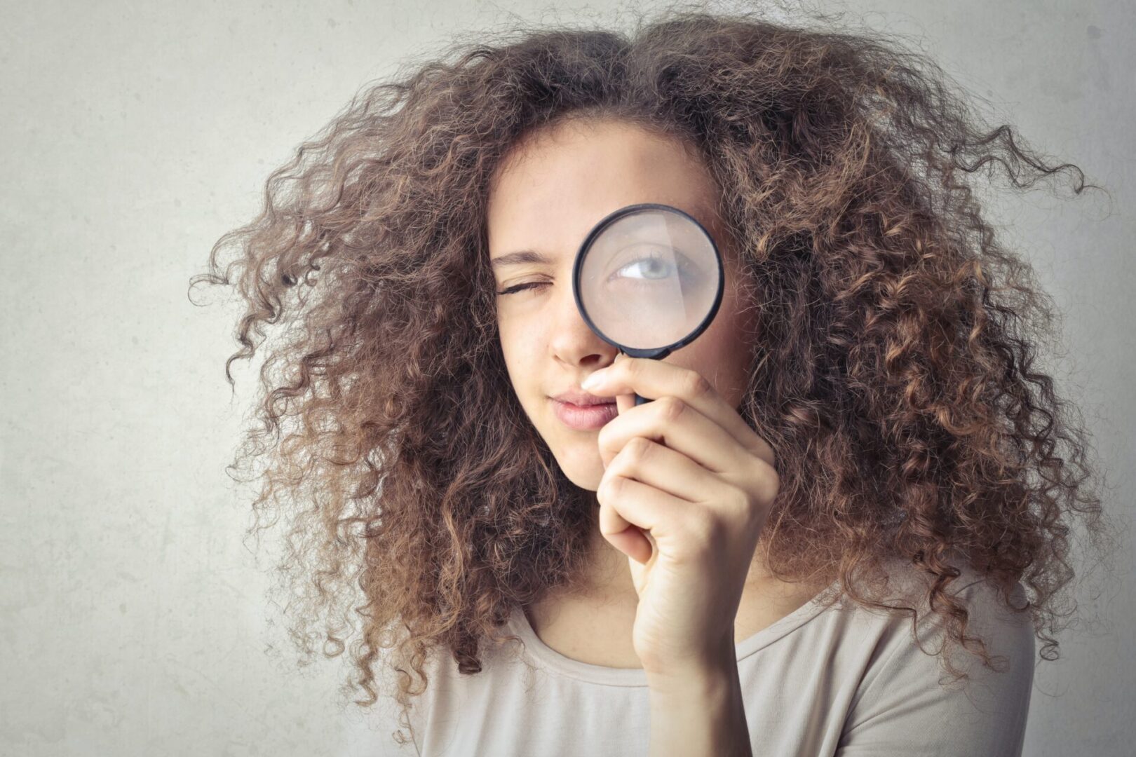 A woman holding a magnifying glass up to her face.