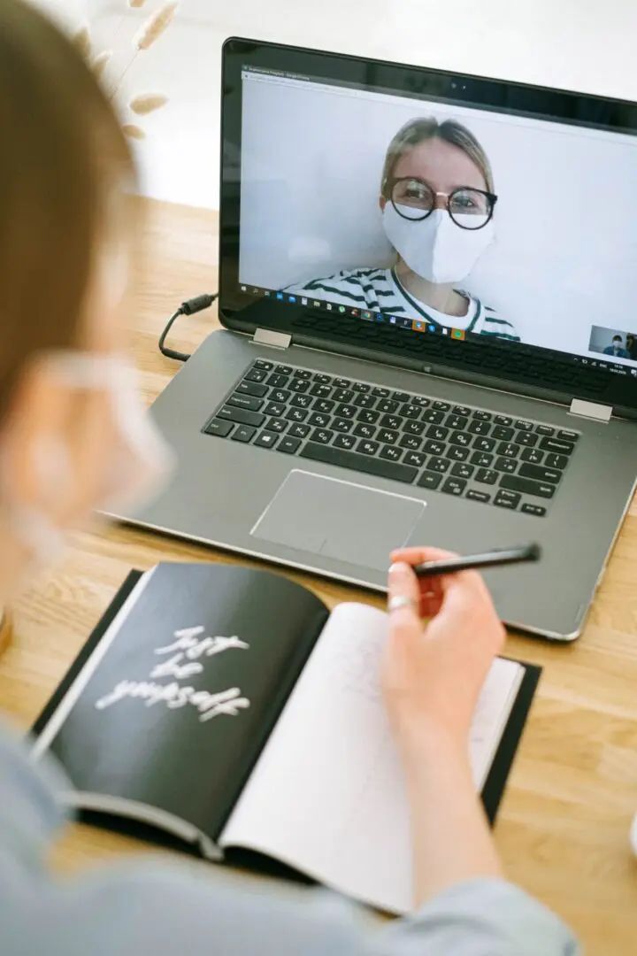 A person is on the computer with a notebook