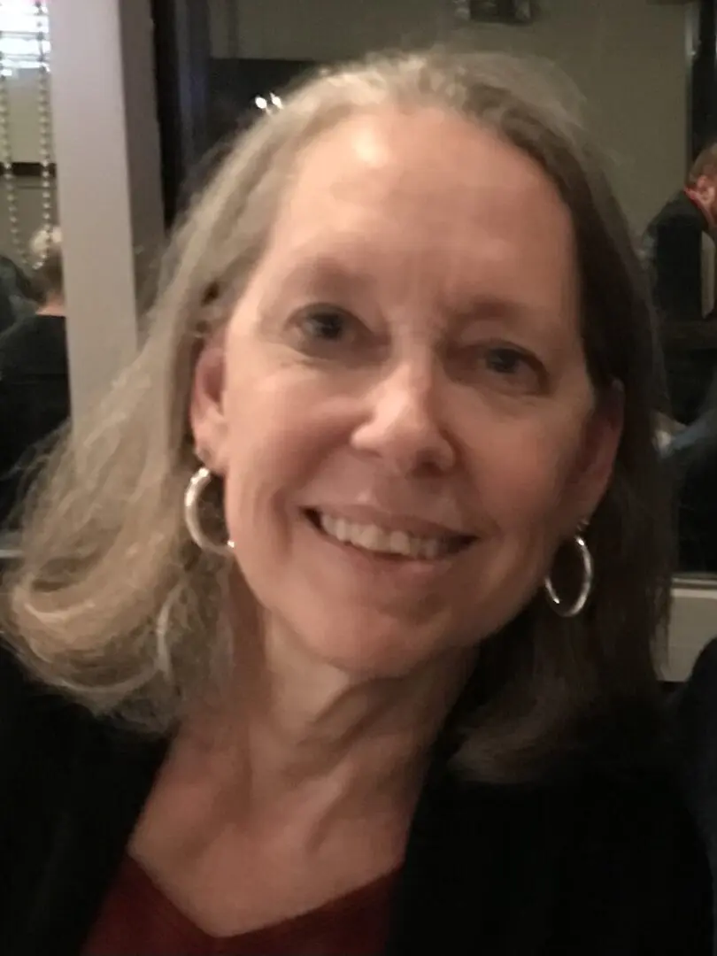 A woman with long hair and large earrings.