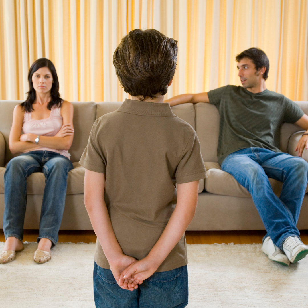 A boy standing in front of two people on the couch