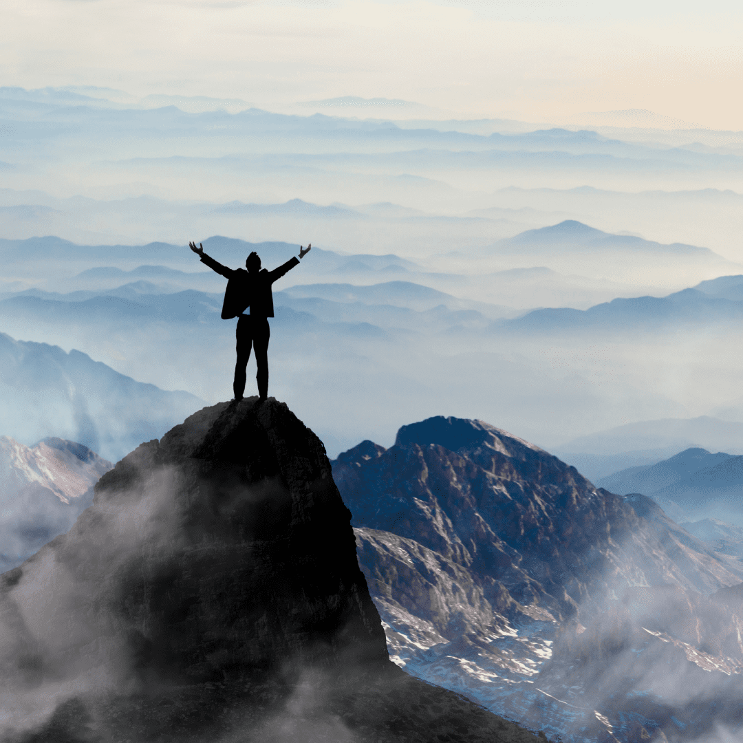 A person standing on top of a mountain with arms outstretched.
