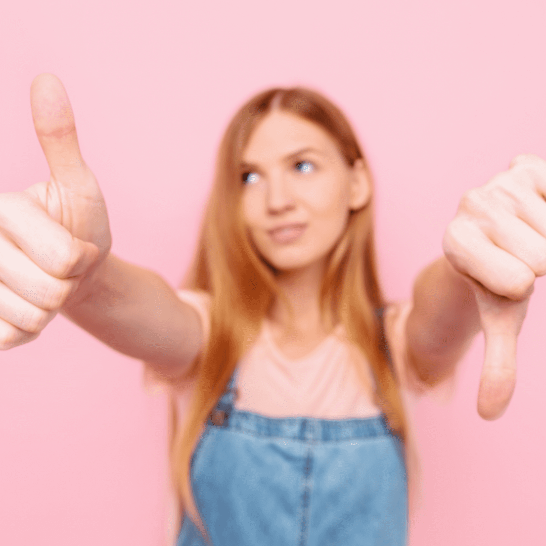 A woman with long hair is holding two thumbs up.