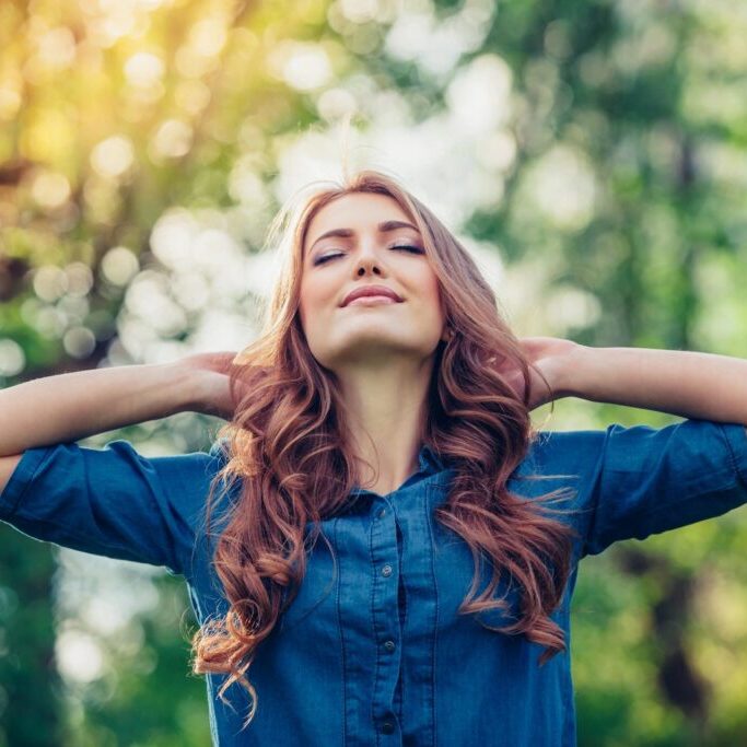 A woman with her hands behind her head.