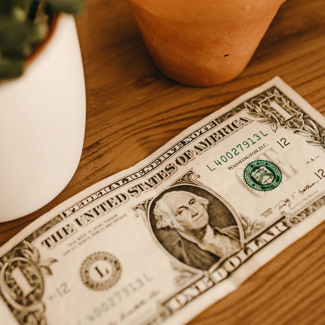 A dollar bill sitting on top of a wooden table.