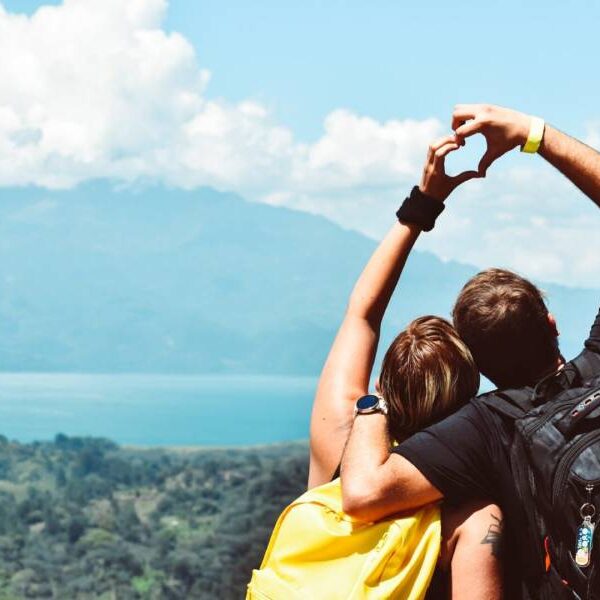 Two people standing on a cliff with their arms in the air.