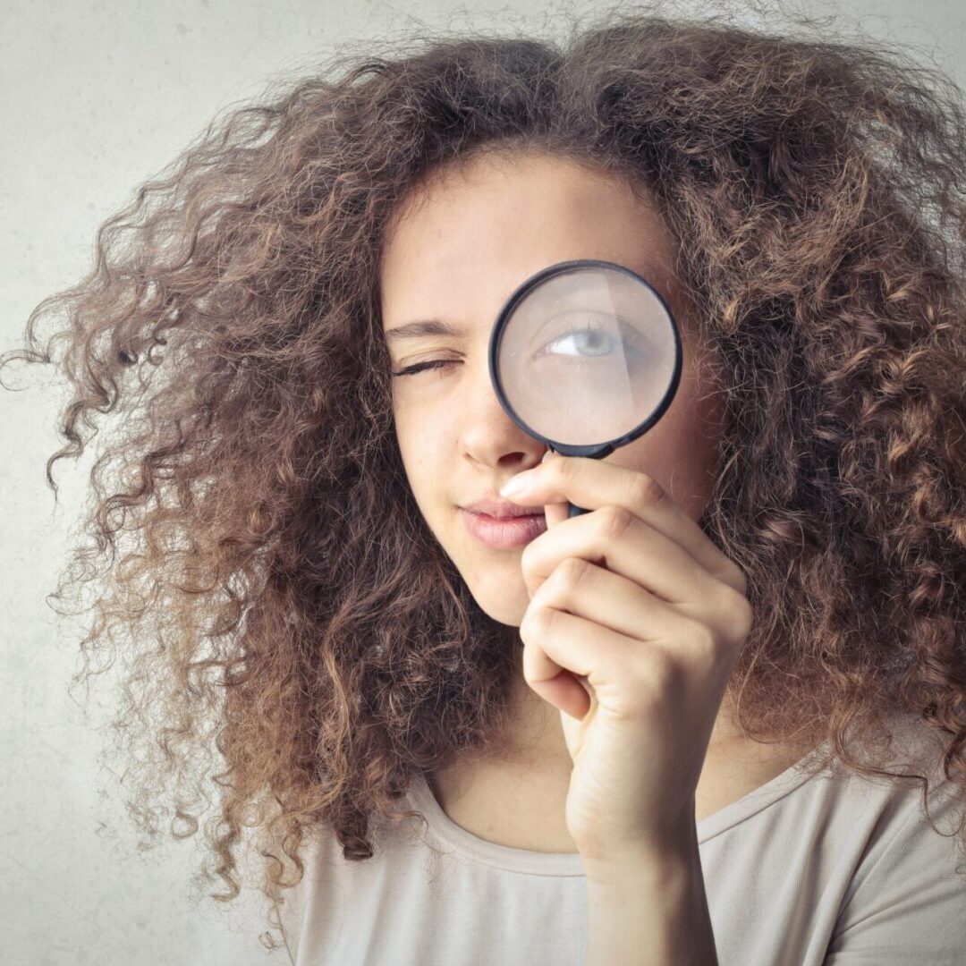 A woman holding a magnifying glass up to her face.